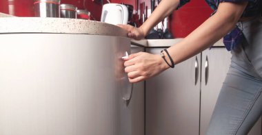 Beyaz kadın mutfak kapısının mobilyalarını açıyor..