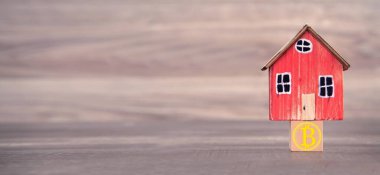 Ahşap küpte Bitcoin sembolü olan ev modeli.