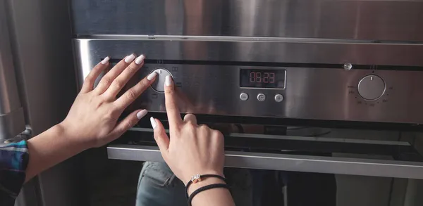 台所の電気オーブンのボタンに触れる女性の指 — ストック写真