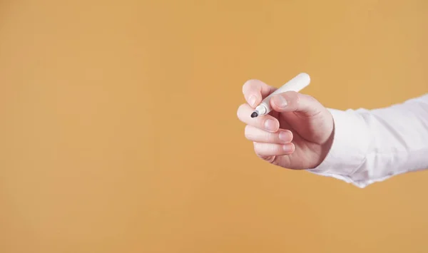 stock image Male hand holding a marker isolated on yellow background.