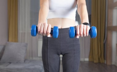 Dambıl tutan bir kadın. Evde egzersiz yap.