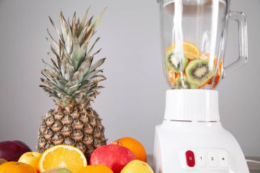 Masanın üzerinde taze meyveler olan beyaz blender..