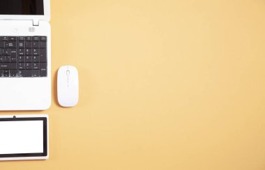 Sarı arkaplanda beyaz dizüstü bilgisayar, tablet ve fare.