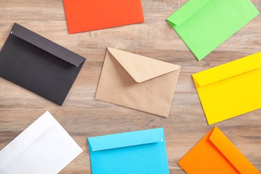 Ahşap arkaplanda renkli posta zarfları.