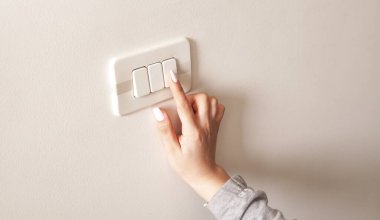 Duvardaki elektrik düğmesini çeviren kadın el..