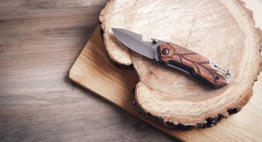 Kahverengi bıçak ve tahta arka planda bir ağaç dilimi..