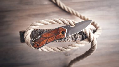 Kahverengi bıçak, ip ve tahta zemin üzerinde bir ağaç dilimi..