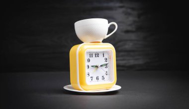 Siyah arka planda kahve fincanı ve saat..