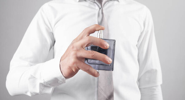 Кавказский элегантный мужчина, распыляющий духи.