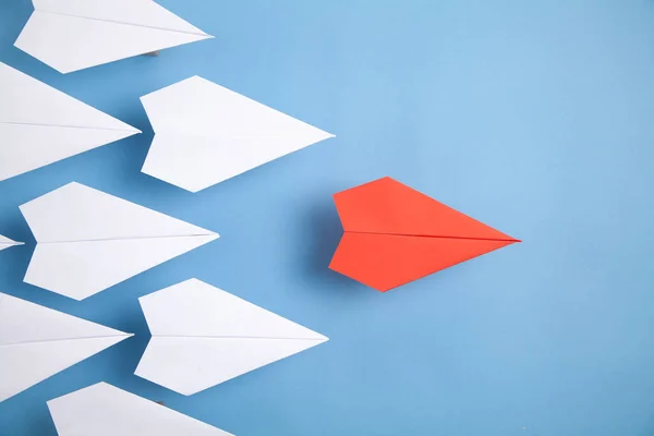 Mavi arka planda kırmızı ve beyaz kağıt uçaklar. Liderlik. Takım çalışması.