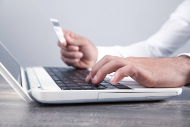 Dizüstü bilgisayar kullanan ve kredi kartı tutan bir iş adamı..