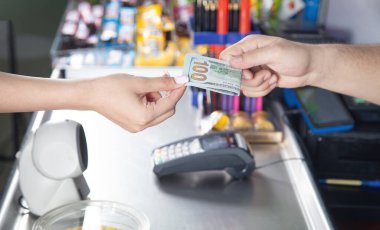 Genç bir kadın süpermarkette para ödüyor..