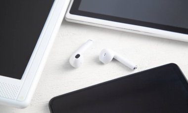 Beyaz kablosuz kulaklık, dizüstü bilgisayar, tablet, akıllı telefon..