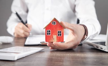 Emlakçı ev modelini tutuyor ve kontrat imzalıyor..