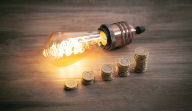 Ampul ve para yığını ahşap arka planda. Enerji ve para tasarrufu 