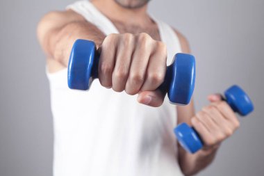 Elinde mavi dambıl tutan beyaz bir adam..