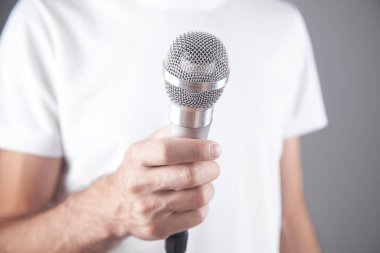 Ofisinde mikrofon tutan beyaz bir adam..