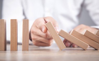 Erkek el, tahta dominoyu durduruyor. İş için. Kriz. Risk