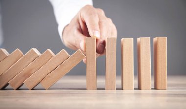 Erkek el, tahta dominoyu durduruyor. İş için. Kriz. Risk