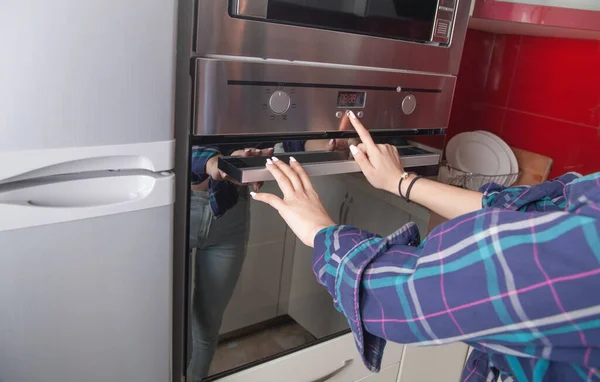 台所の電気オーブンのボタンに触れる女性の指 — ストック写真