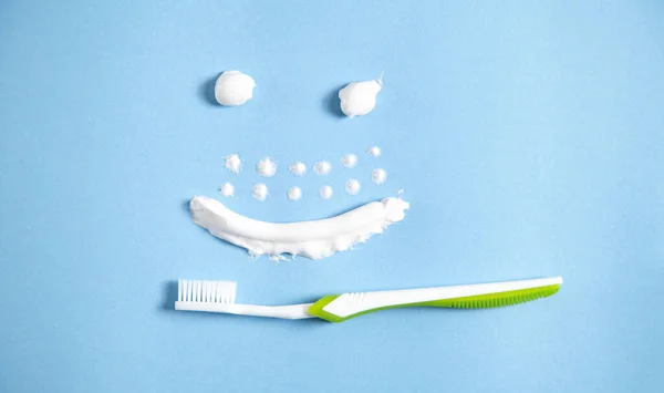Οδοντόβουρτσα Στο Μπλε Φόντο Χαμογελαστό Πρόσωπο Από Οδοντόκρεμα — Φωτογραφία Αρχείου