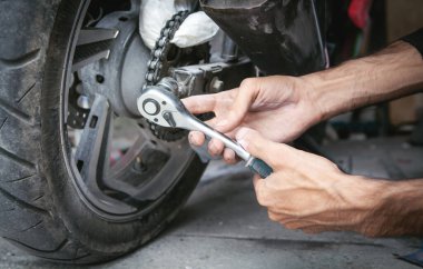 İngiliz anahtarı kullanan bir tamirci. Garajda motosikletle çalışıyorum.
