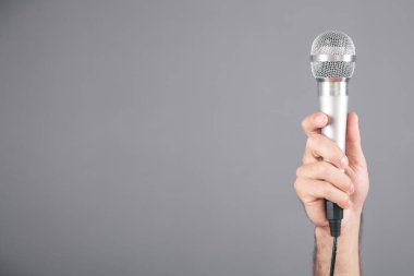 Gri arka planda insan eli mikrofon..