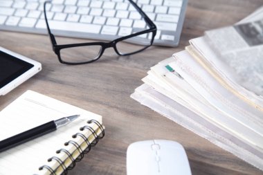 Gazeteler, bilgisayar klavyesi, ahşap masada gözlük.. 