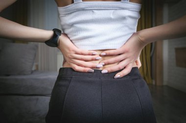 Evde sırt ağrısı çeken genç bir kadın..