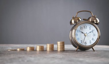 Çalar saat ile sikke yığını.