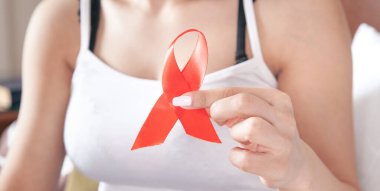 Elinde kırmızı kurdele tutan genç bir kadın. AIDS