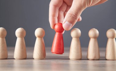 Erkek eli kırmızı ahşap insan figürünü tutuyor. Lider