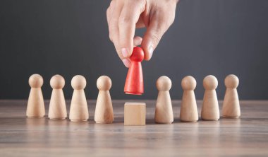 Erkek eli kırmızı ahşap insan figürünü tutuyor. Lider
