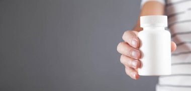 Erkek, elinde ilaç şişesi tutuyor..