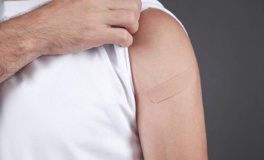 Beyaz bir adam aşıdan sonra omzunu bandajla gösteriyor..