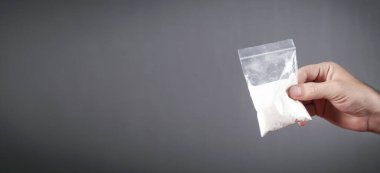 Elinde plastik paket kokain tutan bir uyuşturucu satıcısı..