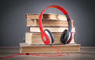 Kitap ve kulaklıklar ahşap masada. Audiobook