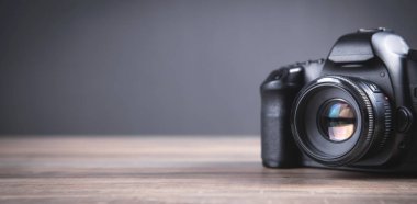 Ahşap masada profesyonel DSLR kamerası var..