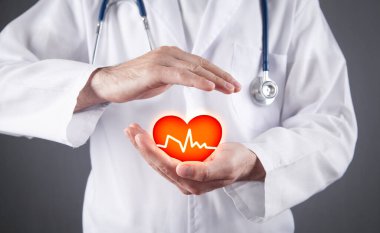 Doktor kırmızı kalbi kardiyogramla tutuyor..