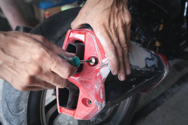 Beyaz adam garajda motosikletini tamir ediyor..