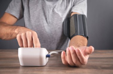 Beyaz bir adam kan basıncını evde ölçüyor..