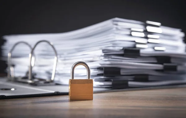 Ahşap masanın üzerinde asma kilit olan dosyalar ve belgeler. Veri güvenliği