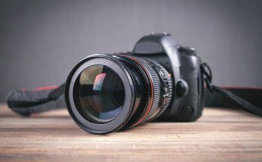 Ahşap masada profesyonel DSLR kamerası var..
