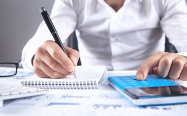 İş adamı analiz pazarlama planı için hesap makinesi kullanıyor.