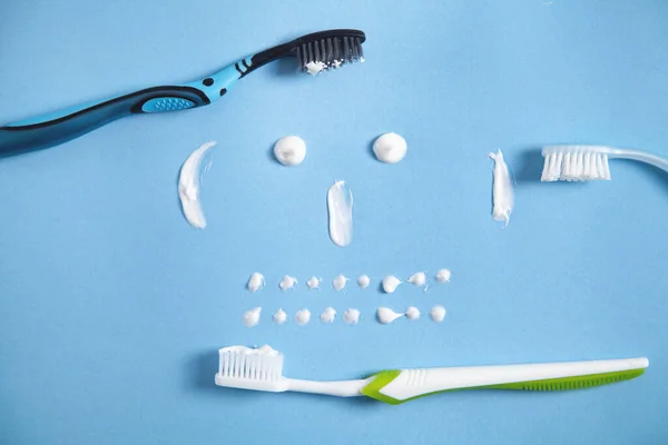Οδοντόβουρτσα Και Οδοντόκρεμα Στο Μπλε Φόντο Χαμογελαστό Πρόσωπο — Φωτογραφία Αρχείου