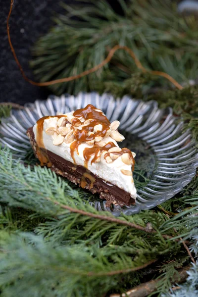 Snickers cake. Piece of nut cake on fir branches. Festive postcard. Macro.