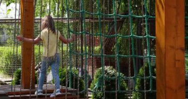 Little girl having fun time in the rope park. Summer camp activity for kids. Adventure park in the forest.
