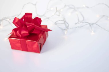 Kırmızı hediye kutusu, arka planında saten kurdele var. Doğum günü hediyesi.