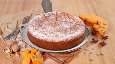 Kadın eli, turtanın arka planında bir dilim balkabağı turtası ve onu yapmak için malzemeler gösterir.