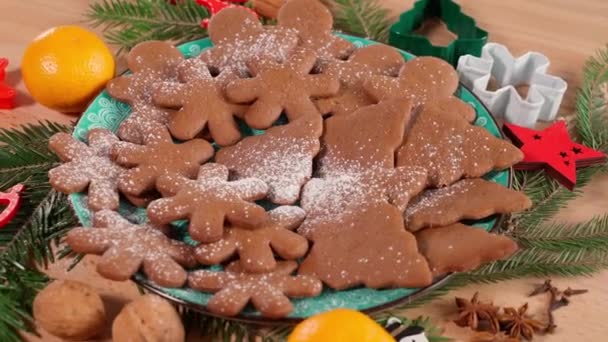 クリスマスのジンジャーブレッドクッキーは 氷砂糖がそれらに滴下し 雪の模倣と回転面上のプレートにあります クリスマスの装飾が施されたテーブル — ストック動画